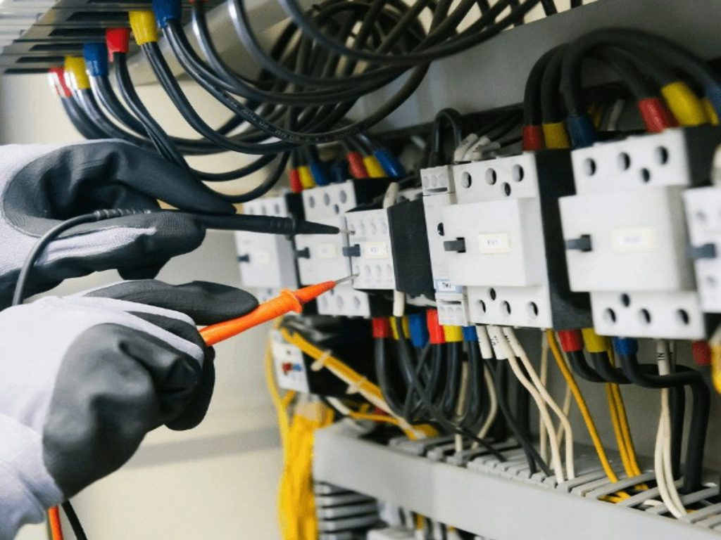 electrician working on wiring inside a control panel