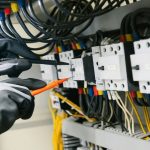 electrician working on wiring inside a control panel